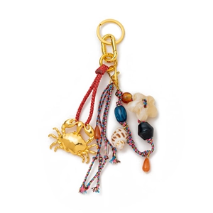 Detailed shot of a luxury keychain with a golden crab pendant and colorful braided ropes