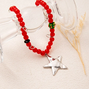 Handmade red beaded necklace with green accents and a large silver star pendant