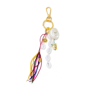 Detail of bohemian bag charm featuring seashells, gold pendants and a colorful tassel