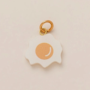 Detailed view of creative fried egg pendant with polished golden ring and resin finish