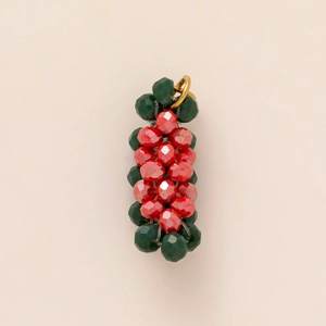 Gedetailleerde weergave van rood-groene kralenhanger met gouden ring op beige basis