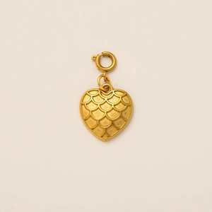 Détail d'un pendentif cœur doré vintage avec texture écaille et fermoir rond