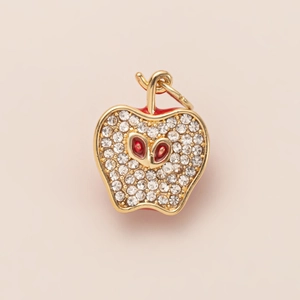 Detailed macro of gold apple charm with micro-pave white zircons and red gem accents