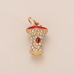 Macro shot of apple core pendant with gold finish, red enamel, and sparkling crystals