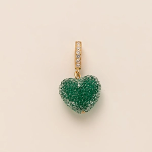 Detailed view of heart-shaped pendant with green crystals and gold zircon-set bail