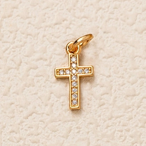 Détail d'un pendentif croix en cuivre doré serti de zircons cubiques ronds étincelants