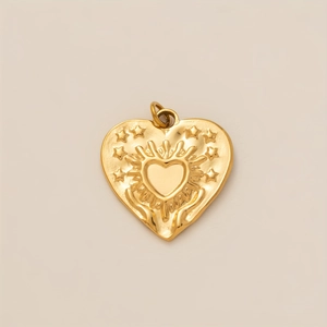 Dettaglio macro di un ciondolo a cuore placcato oro 18K con texture a raggiera e stelle