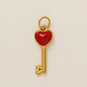 Detail of a vintage golden heart-shaped key pendant with vibrant red enamel inlay