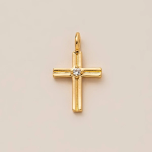Détail du pendentif croix plaqué or avec un zircon central et des textures verticales