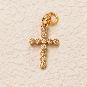 Vue macro d'un pendentif croix plaqué or orné de pierres de zircone cubique rondes