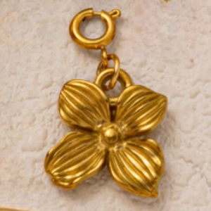 Dettaglio macro di un ciondolo a fiore placcato oro 18K con perla su fondo pietra
