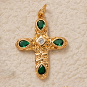 Detail of gold cross pendant with hammered texture and green pear-shaped gemstones