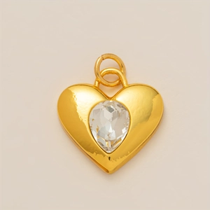 Dettaglio di un ciondolo a cuore placcato oro 18K con una pietra di cristallo a goccia