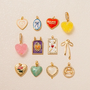 Detailansicht von 12 goldenen Herzanhängern und Schleifen mit Emaille- und Tarot-Motiven