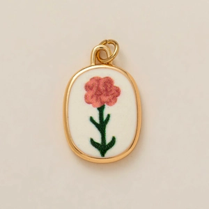Détail d'un pendentif ovale vintage en or avec fleurs roses sur fond beige uni