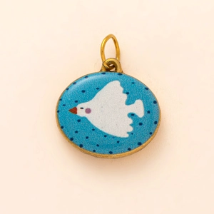 Detail eines hellblauen Emaille-Anhängers mit weißem Vogel und dunkelblauen Punkten
