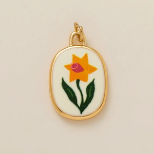 Détail du pendentif ovale doré avec motif jonquille jaune sur émail blanc élégant