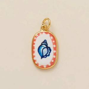Nahaufnahme eines goldenen ovalen Anhängers mit blauem Muschelmuster und roten Punkten