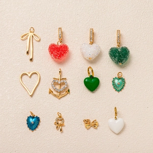 Detailed flat lay of assorted gold heart and bow pendants with crystals and enamel