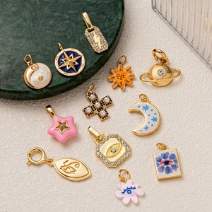 Collection of golden stainless steel pendants with celestial motifs on marble