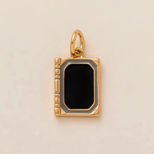 Macro shot of gold book charm featuring a black enamel center and ribbed spine detail
