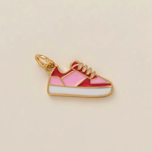 Macro detail of high-quality gold plated sneaker charm with vibrant pink enamel finish