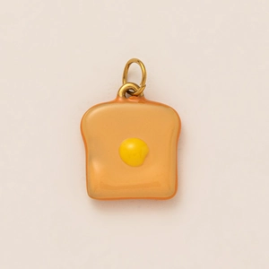 Détail d'un pendentif créatif en forme de toast et œuf au plat en acier inoxydable poli