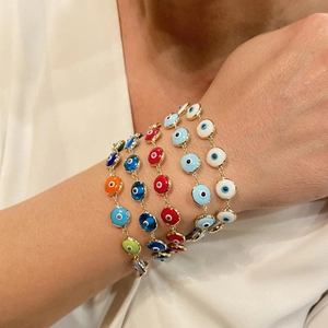 Close-up of a model wearing four colorful Evil Eye bracelets with gold-plated chains