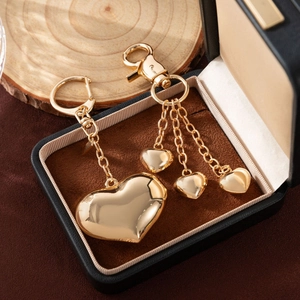 Polished golden heart-shaped pendant set with metallic fringe tassels in a luxury box