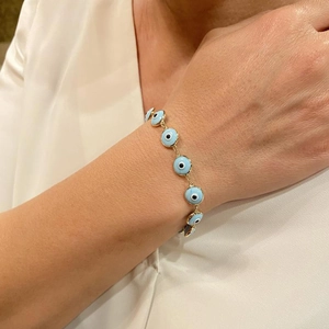 Minimalist gold chain evil eye bracelet with light blue beads on a female wrist
