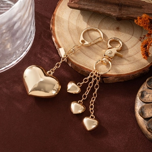 Detail of gold heart bag charms with lobster clasps on a stylish wooden tray