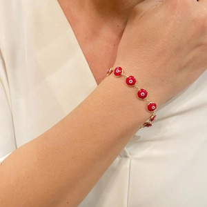 Close-up of red Evil Eye enamel bracelet on model with golden chain and charms