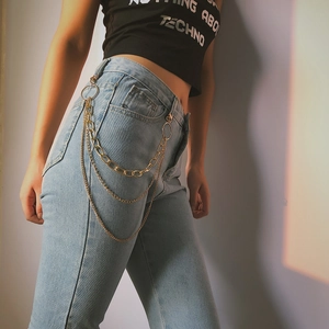 Nahaufnahme der dreilagigen goldenen Hüft-Metallketten auf hellblauer Jeans im Hip-Hop-Stil