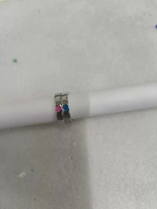 Dettaglio anelli di coppia con cuori in smalto rosa e blu e fasce argentate regolabili