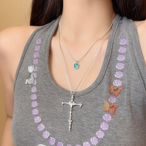 Detailed close-up of a double layered gothic skull cross necklace with blue stone pendant