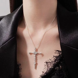 Macro shot of gothic silver skeleton cross pendant on a black satin suit background