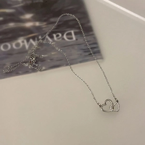 Dettaglio del pendente a doppio cuore intrecciato con pavé di zirconi cubici brillanti