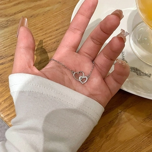 Collana d'argento con cuori intrecciati e cristalli pavé, mostrata sul palmo della mano
