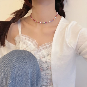 Detailopname van kleurrijke kralen choker ketting op model in witte kanten kledingstuk