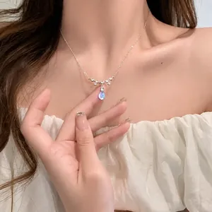 Detailed close-up of a teardrop moonstone pendant on a silver necklace worn by a model