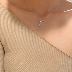 Detail of teardrop moonstone pendant on silver chain worn by model on neck