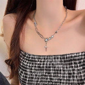 Detail of cross and moonstone necklace on model neck showing layered chain texture