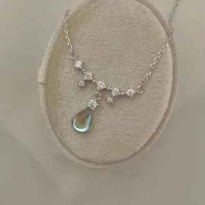 Detailed view of teardrop moonstone pendant with V-shaped sparkling zircon on beige velvet