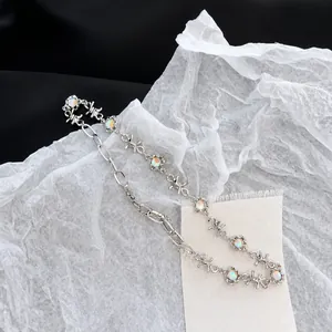 Détail du collier à chaîne épineuse argentée avec pierre de lune sur fond beige neutre