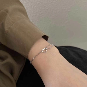 Detail of silver double-layer heart bracelet featuring bead and link chain styling