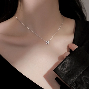Close-up of a silver four-leaf clover pendant necklace featuring sparkling zircon inlay