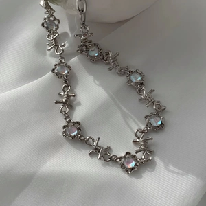 Détail macro d'une chaîne barbelée avec pendentif pierre de lune sur soie blanche pure