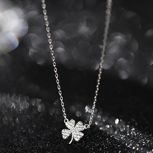 Macro shot of silver four-leaf clover pendant with pavé crystal inlay on a delicate chain