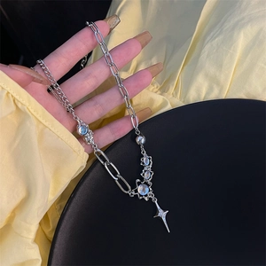 Close-up of asymmetrical silver chain with moonstone beads and star pendant on skin