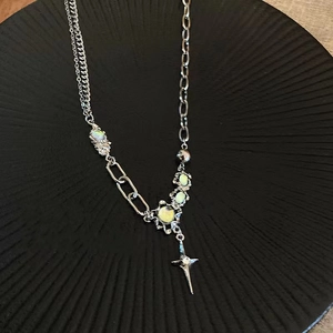Detail of silver asymmetric necklace with light green stone and star cross pendant